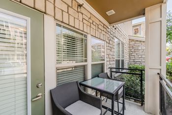 A patio with a glass table and two chairs